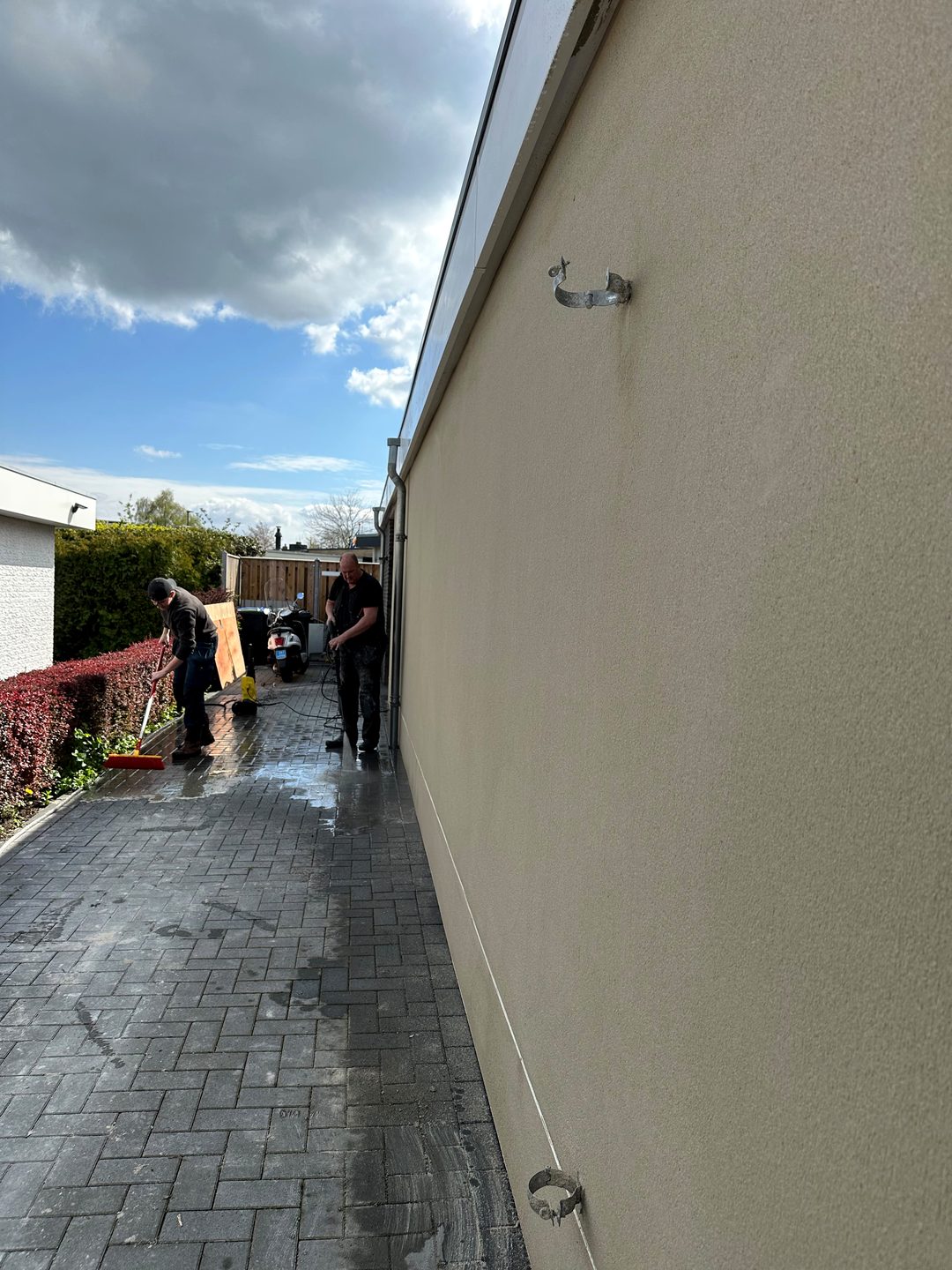 Gestucte zijgevel van de bungalow terwijl de bestrating wordt schoongemaakt