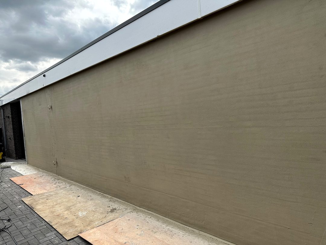 Lange zijgevel van een bungalow, gestuct in een zandkleurige tint