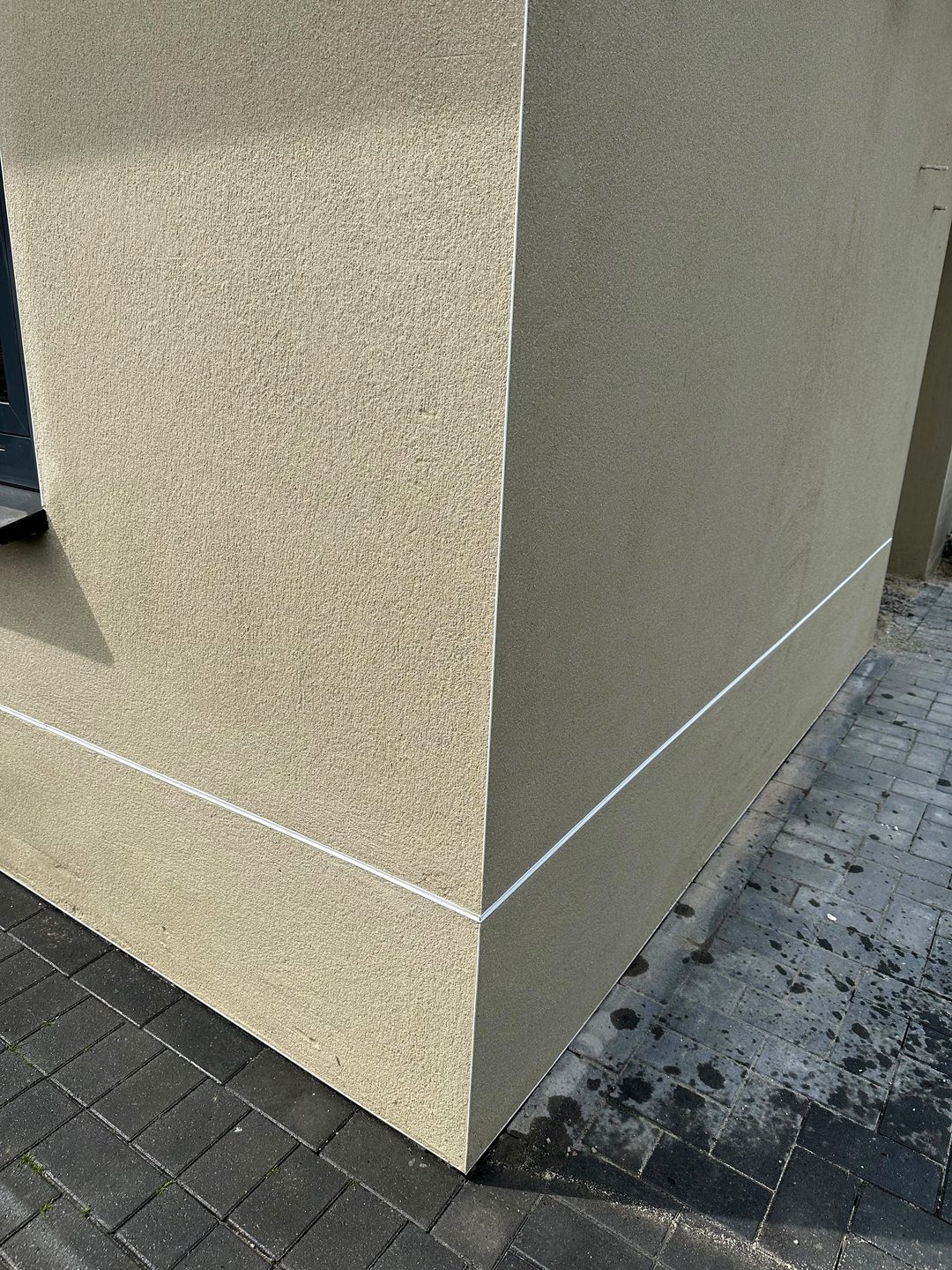 Detail van een gestucte gevelhoek met een strakke plintlijn