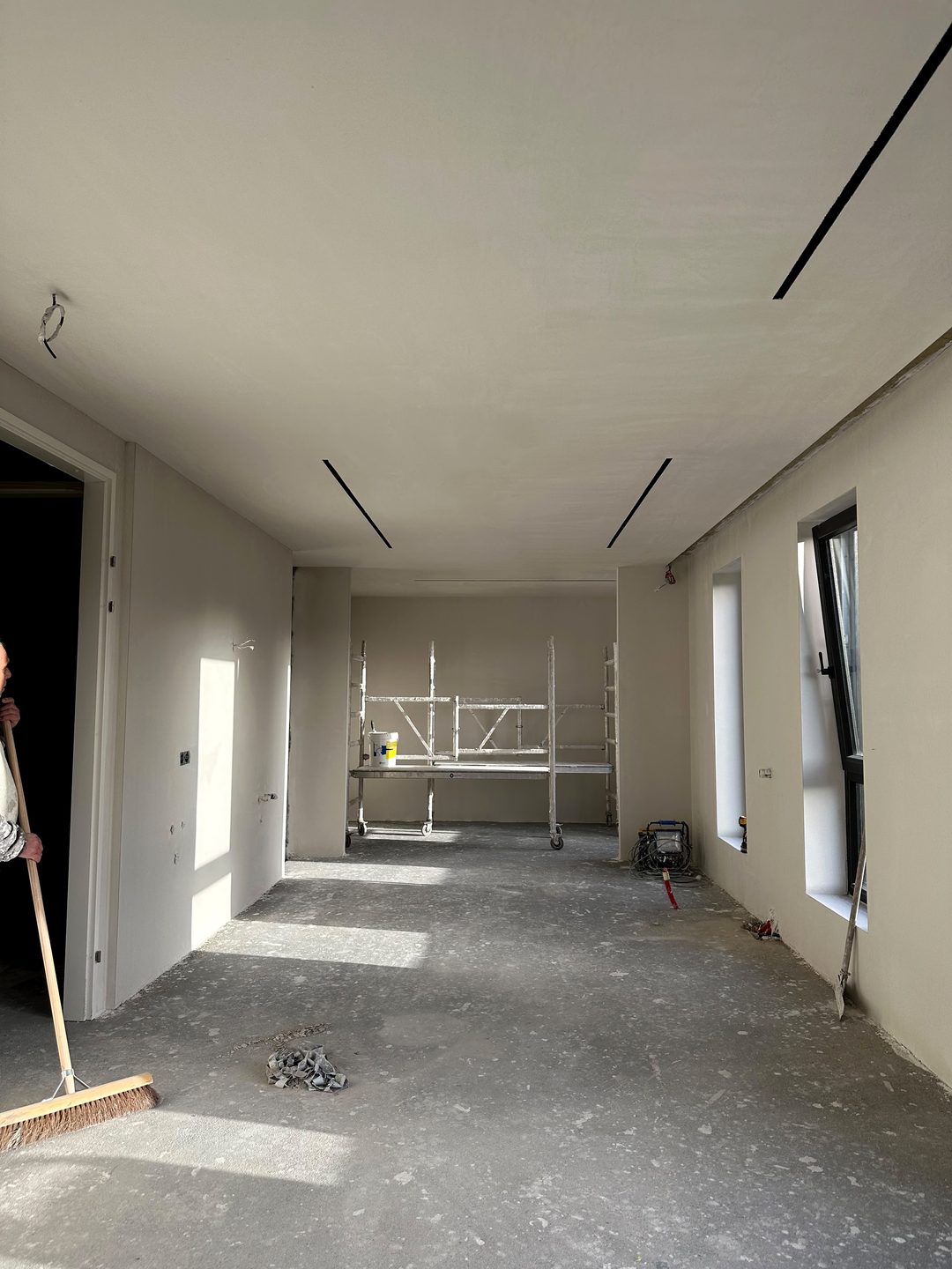 Dezelfde ruimte na het stucwerk: strakke wanden en een glad plafond met zwarte lichtlijnen