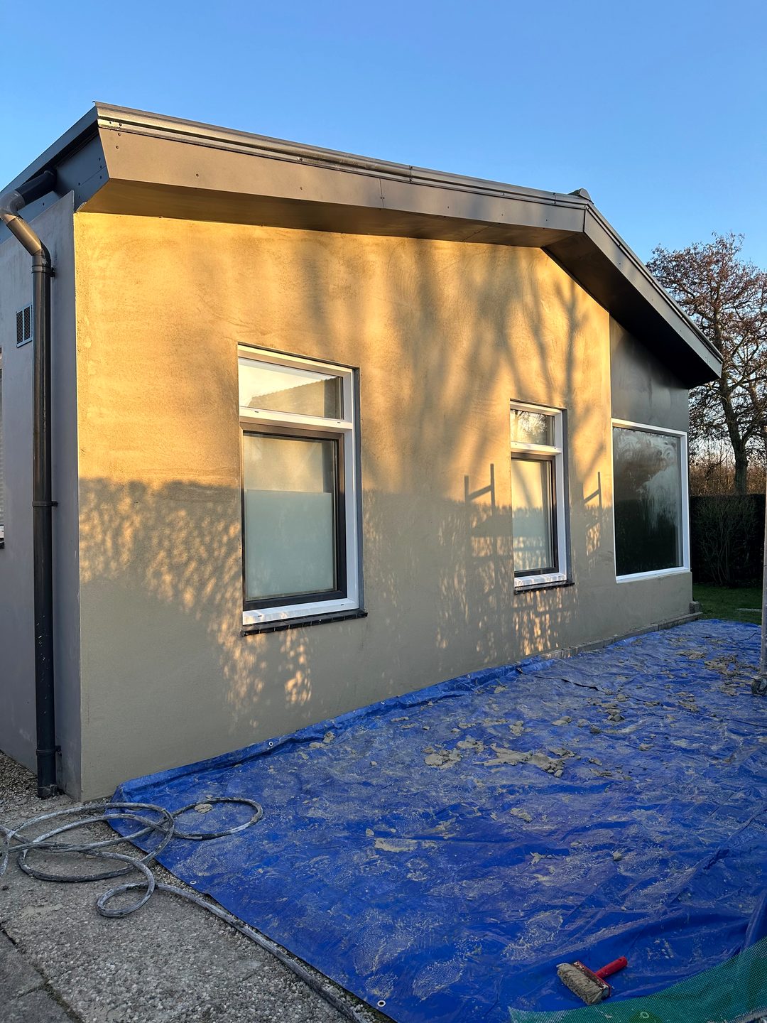 Dezelfde woning met afgewerkte gestucte buitengevel in de avondzon
