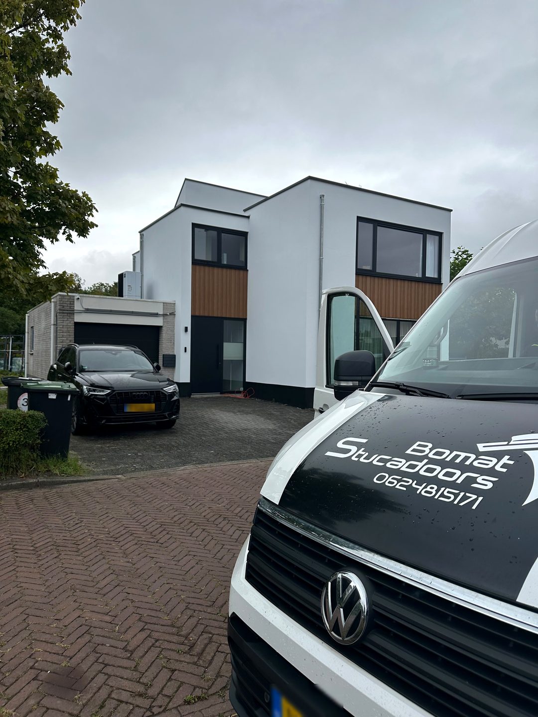 Moderne woning met strak wit afgewerkte gevel, met de bus van Bomat op de voorgrond