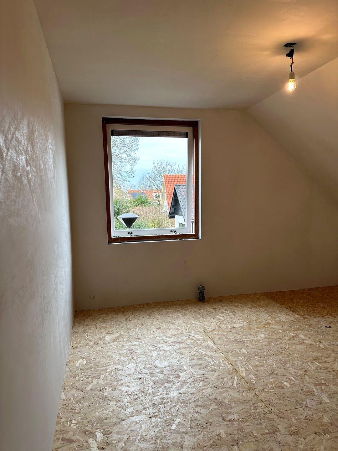 Zolderkamer met pas gestucte wand, gezien langs de zijwand